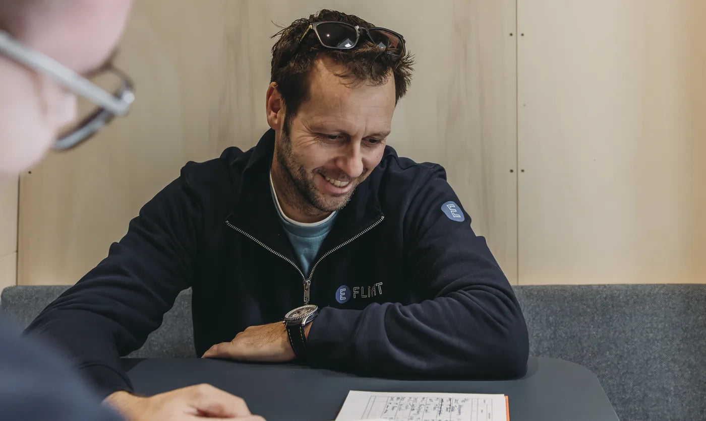 Instructeur bespreekt lachend het logboek met een student in E-Deck